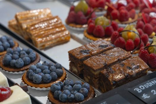 Colorful display of pastries topped with fruits. Shallow depth of field