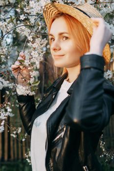 Portrait of a woman in a straw hat in a cherry blossom. Free outdoor recreation, spring blooming garden.