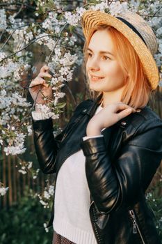 Portrait of a woman in a straw hat in a cherry blossom. Free outdoor recreation, spring blooming garden.