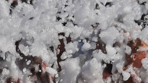 Foam entertainment party, people cheerfully raise their hands, catch soap bubbles, summer entertainment festival in the water park. Happy people are happy in summer. Sardinia island. background and texture. High quality photo