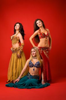 Three young dancer in oriental arabian costume on red