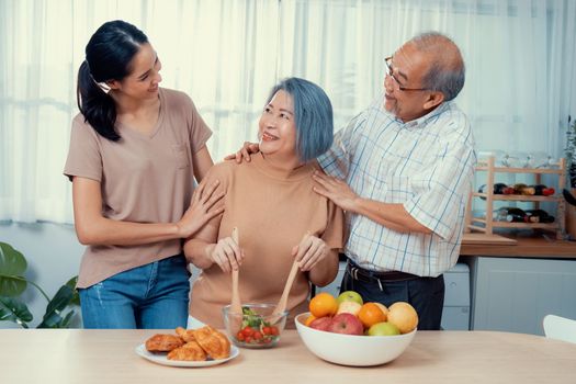 Contented family, daughter, father, mother prepare bread veggies and fruit salad together in their kitchen.