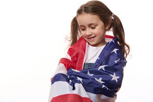 Lovely baby girl, a little American citizen wraps herself in USA flag, celebrates Independence Day, 4th July. Human rights and freedoms, isolated over white background with space for your promotion