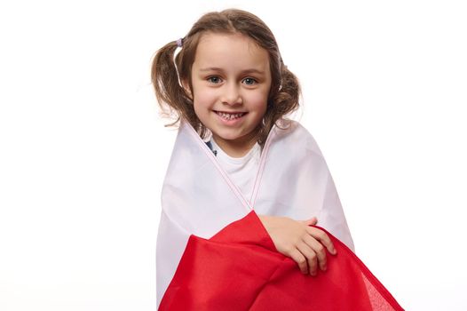 European Polish little citizen, a lovely child, baby girl wrapping flag of Poland, celebrates the Independence Day on November 11th, isolated over white background with copy space for promotional text