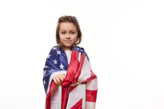 Isolated portrait on white background of a happy American little girl with USA flag and suitcase. Citizenship, immigration, emigration, study in America, winning green card lottery and freedom concept