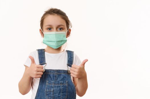 Isolated portrait on white background of toddler, kid girl wearing medical protective mask, against air smog pollution. Protection against virus. Infection control concept. Healthcare and medicine