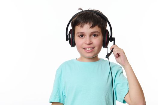 Isolated portrait on white background of a handsome dark-haired multi-ethnic child boy, wearing audio headset during a video class, smiling looking at camera. Children and technology. Online education