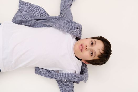 Top view multi-ethnic dark-haired brown-eyed adorable teen boy in white t-shirt and blue shirt, looking at camera, isolated on white background with free advertising space for promotional text
