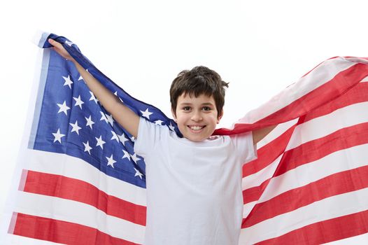 Multiethnic happy patriotic preteen child boy, smart teenager, smiling a cheerful toothy smile, looking at camera, carrying American flag. Citizenships. Immigration concept. 4th July. Independence Day