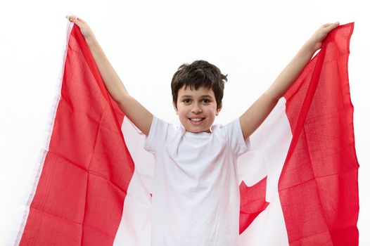 Happy Canadian citizen, a teenage boy wearing casual t-shirt and blue denim jeans, carrying a flag of Canada, celebrating the independence Day on July 1. Concept of freedom, liberty and citizenships