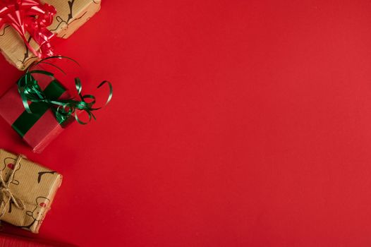 Christmas still life with gifts in the corner of a red background. Copy ad space. Mockup, layout for promotional text. Boxing Day. Xmas and New Year's preparations. Packing gifts. Web banner. Flat lay