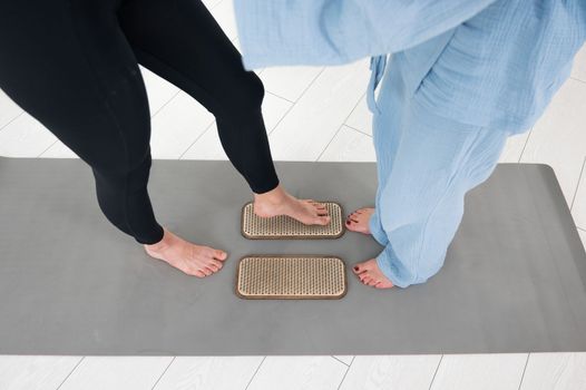 Caucasian woman stands on sadhu boards with therapist support