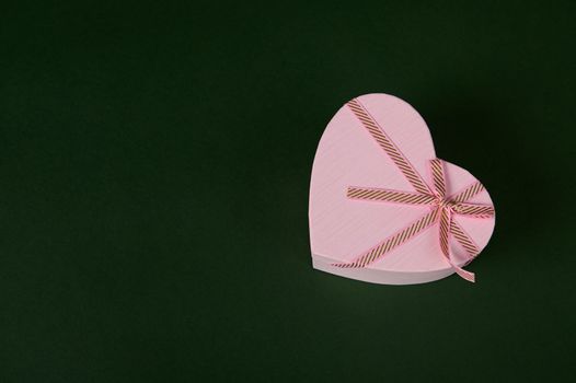 Flat lay. Still life with cute romantic present in heart shaped pink gift box for Saint Valentine's or Women's Day, on green background, copy ad space. Celebration. Festivity. Spring, winter holidays