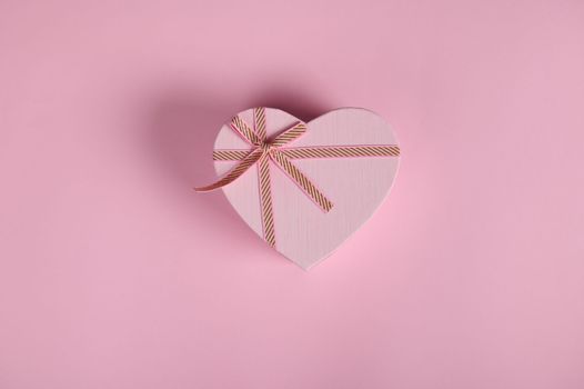 Flat lay with Valentine's Day love gift, in a heart shaped box. February 14. Still life on pink background with copy ad space. Romantic present for Women's Day in March 8