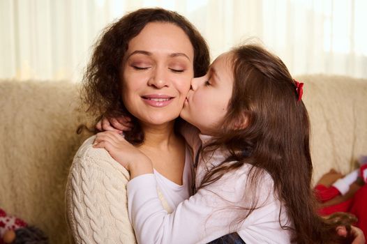 Lovely baby girl gently hugs and kisses her loving mother. Carefree childhood. International Children's Day. Happy family relationships. Affectionate woman with her daughter together. Love Tenderness