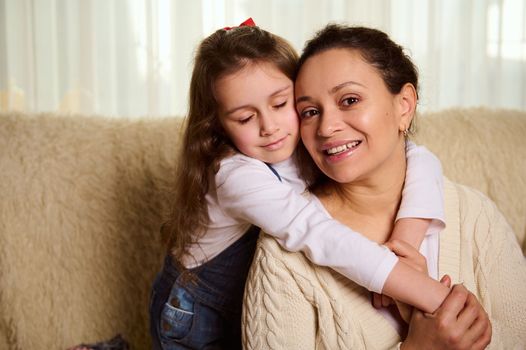 Adorable Caucasian little girl, a lovely daughter gently hugging her mom. Concept of International Mother's and Children's Day. Happy childhood and conscious motherhood. Family relationships. Love