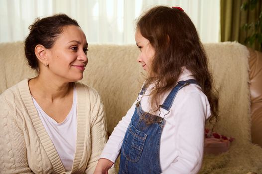 Beautiful multi-ethnic woman, a loving mother talking with her cute daughter, a lovely baby girl, looking at her with tenderness and love. Happy family relationships. Carefree childhood. Motherhood