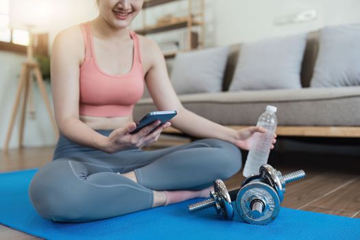 Healthy asian woman practicing relaxation yoga at home. Spending time and playing phone at home concept.