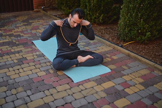 Portrait of a yogi, sitting on a fitness mat during a yoga practice. Healthy and active lifestyle. Mindfulness. Awakening. Enlightenment. Spiritual growth. Healthy lifestyle. Body conscious