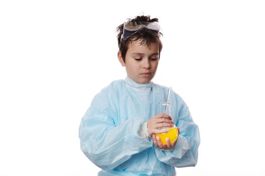 Confident smart pupil, a young chemist scientist teenage boy in labwear, mixing chemical solution in a laboratory flask with glass stick, isolated over white background. Chemistry. Science. Education