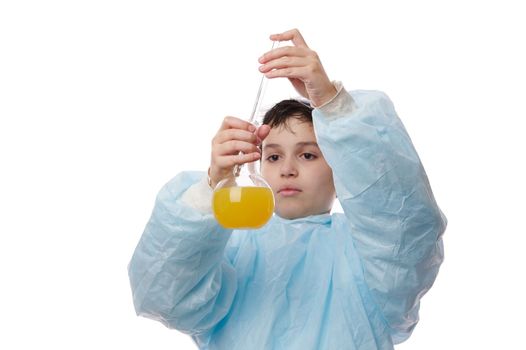 Selective focus on the hands of a teenage boy filling a pipette with yellow chemical liquid from a lab flask, dropping the reagent, while doing a chemistry experiment in scientific school laboratory