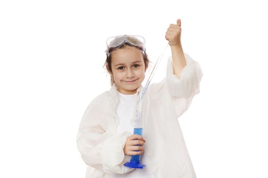 Adorable little girl , smart student chemist-scientist wearing lab coat, dripping few drops of reagent from graduated pipette into a measuring cylinder with chemical solution, at a chemistry lesson