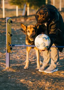 Concept: child and dog. Cute boy plays and teaches the dog to jump over obstacles. Teamwork.Concept: child and dog. Cute boy plays and teaches the dog to jump over obstacles. Teamwork.