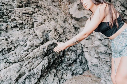 A girl climbs a rock. The athlete trains in nature. Woman overcomes difficult climbing route. Extreme hobby. Tourist woman rock climber hiking on mountains rocks over beautiful sea coast