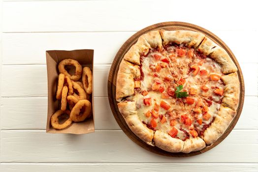 Delivery Concept. Neapalitan pizza with tomatoes on white with appetizers. Set pizza and appetizers side by side on white top view.