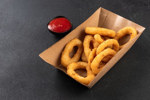 squid rings in a paper box on a dark background. Home delivery concept.