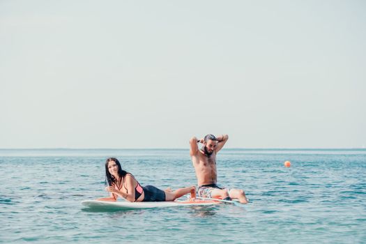 Silhouette of woman standing, surfing on SUP board, confident paddling through water surface. Idyllic sunset or sunrise. Sports active lifestyle at sea or river.