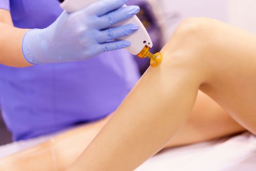 Woman receiving legs laser hair removal at a beauty center. Laser depilation treatment in an aesthetic clinic.