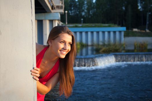 Young beauty woman in red near concrete dam look at sunset