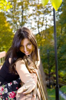 Beauty woman in autumn park stand on bridge