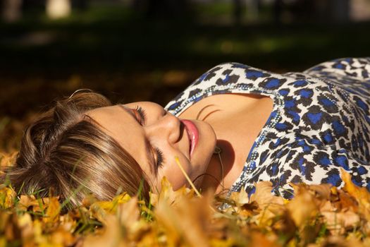 woman lay on ground in autumn leaves