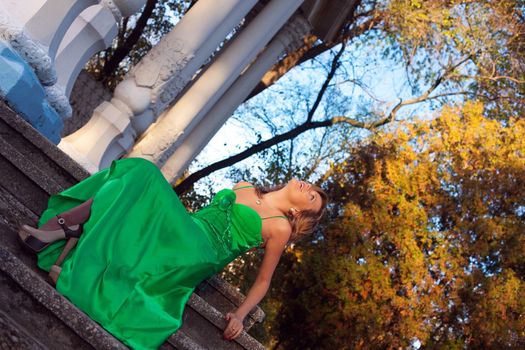 Beauty woman in green clothes sit on stair in autumn park