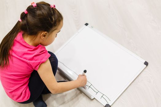 little girl writing on the white board, schooling background.