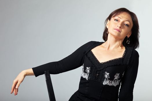 mature woman sit and relax on chair in lace jacket