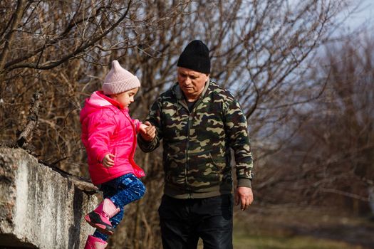 Senior man with his granddaughter. Child and grandpa outdoors. Benefits of getting older.