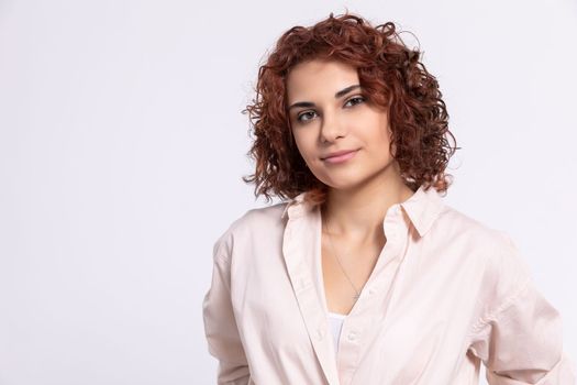 A gentle smile on her face. A European woman with chestnut-colored hair. A girl with fair skin and curly short hair looks straight ahead.