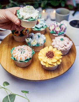 Woman holding a tasty fresh cupcake decorated with flower icing on beautiful wedding party table, high tea,Mothers day Holiday sugar