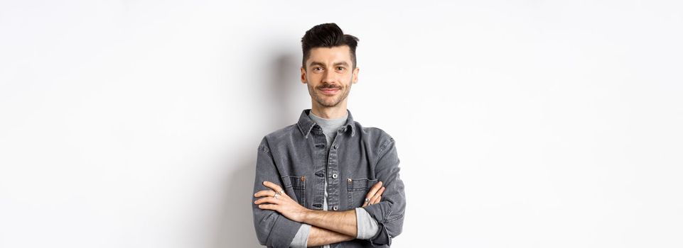 Confident handsome guy in casual outfit cross arms on chest, smiling pleased, standing professional on white background.