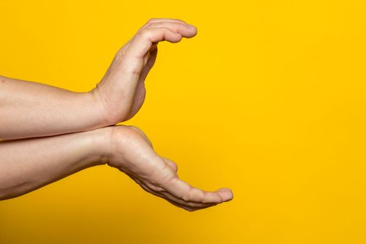 Strong male hands making the gesture of a kame hame, ready to launch a vital wave of energy. Isolated on yellow background