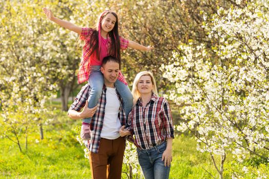 Happy family spending good time together in spring in a flowering garden.