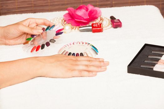 Hands of a woman who chooses the color of her nail polish