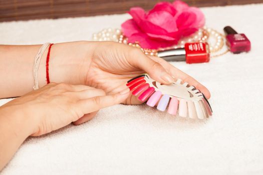 Hands of a woman who chooses the color of her nail polish