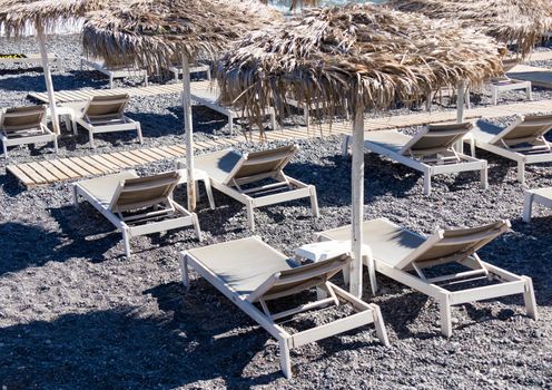 beach with umbrellas and deck chairs in Santorini