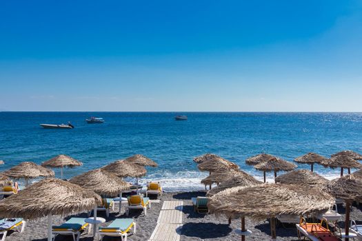 beach with umbrellas and deck chairs in Santorini