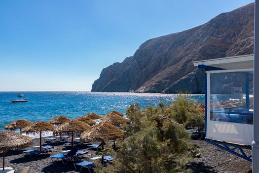 beach with umbrellas and deck chairs in Santorini