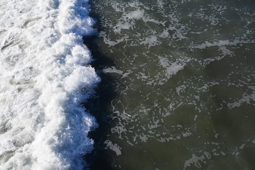 top view of foam of coastal wave when it hit a beach